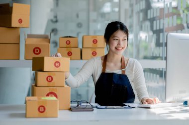 Güzel bir Asyalı işletme sahibi online bir dükkan açıyor, müşterilerin siparişlerini kontrol ediyor, bir kurye şirketi aracılığıyla mal gönderiyor, bir kadının online iş kurma kavramı.