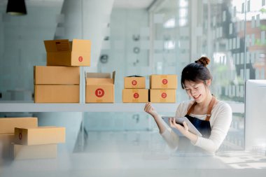 Güzel bir Asyalı işletme sahibi online bir dükkan açıyor, müşterilerin siparişlerini kontrol ediyor, bir kurye şirketi aracılığıyla mal gönderiyor, bir kadının online iş kurma kavramı.