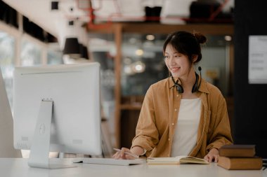 İnternette çalışmak için bilgisayar kullanan güzel bir Asyalı kadın, çevrimiçi çalışıyor. Sınıfta bir salgını önlemek için COVID-19 salgını nedeniyle çevrimiçi öğrenme kavramı.