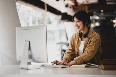 İnternette çalışmak için bilgisayar kullanan güzel bir Asyalı kadın, çevrimiçi çalışıyor. Sınıfta bir salgını önlemek için COVID-19 salgını nedeniyle çevrimiçi öğrenme kavramı.