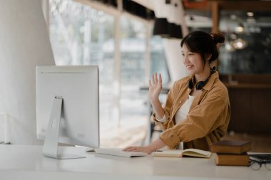 İnternette çalışmak için bilgisayar kullanan güzel bir Asyalı kadın, çevrimiçi çalışıyor. Sınıfta bir salgını önlemek için COVID-19 salgını nedeniyle çevrimiçi öğrenme kavramı.