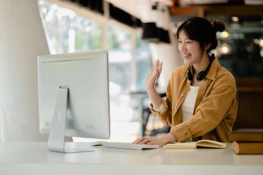 İnternette çalışmak için bilgisayar kullanan güzel bir Asyalı kadın, çevrimiçi çalışıyor. Sınıfta bir salgını önlemek için COVID-19 salgını nedeniyle çevrimiçi öğrenme kavramı.