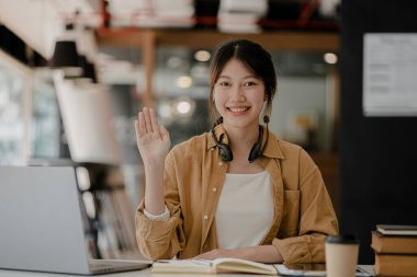 İnternette çalışmak için bilgisayar kullanan güzel bir Asyalı kadın, çevrimiçi çalışıyor. Sınıfta bir salgını önlemek için COVID-19 salgını nedeniyle çevrimiçi öğrenme kavramı.