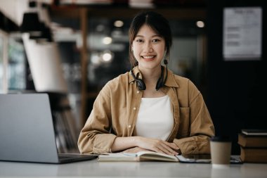 İnternette çalışmak için dizüstü bilgisayar kullanan güzel bir Asyalı kadın, çevrimiçi çalışıyor. Sınıfta bir salgını önlemek için COVID-19 salgını nedeniyle çevrimiçi öğrenme kavramı.