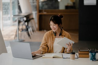 İnternette çalışmak için bilgisayar kullanan güzel bir Asyalı kadın, çevrimiçi çalışıyor. Sınıfta bir salgını önlemek için COVID-19 salgını nedeniyle çevrimiçi öğrenme kavramı.