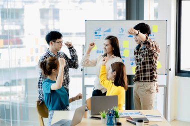 Bir grup girişimci şirket çalışanı konferans odasında şirketin satışlarına ve kârlı sonuçlarına baktıktan sonra memnuniyetlerini göstermek için ellerini kaldırıyorlar. Girişim şirketi konsepti.