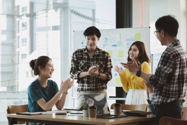 Girişimci şirket çalışanlarından oluşan gruplar konferans odasındalar, şirketin satışları ve kârlılığına baktıktan sonra sevinçlerini göstermek için el çırpıyorlar. Girişim şirketi konsepti.