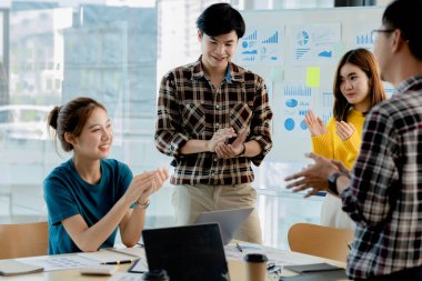 Girişimci şirket çalışanlarından oluşan gruplar konferans odasındalar, şirketin satışları ve kârlılığına baktıktan sonra sevinçlerini göstermek için el çırpıyorlar. Girişim şirketi konsepti.