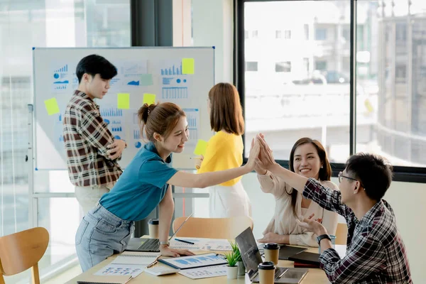 Girişimci şirket çalışanlarından oluşan gruplar konferans odasındalar, şirketin satışları ve kârlılığına baktıktan sonra sevinçlerini göstermek için el çırpıyorlar. Girişim şirketi konsepti.