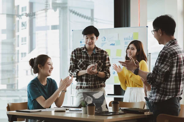 Girişimci şirket çalışanlarından oluşan gruplar konferans odasındalar, şirketin satışları ve kârlılığına baktıktan sonra sevinçlerini göstermek için el çırpıyorlar. Girişim şirketi konsepti.