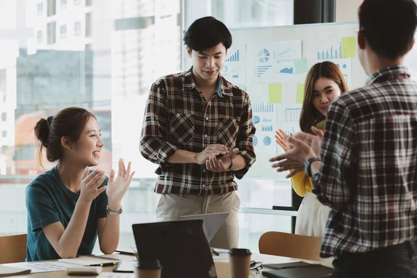Girişimci şirket çalışanlarından oluşan gruplar konferans odasındalar, şirketin satışları ve kârlılığına baktıktan sonra sevinçlerini göstermek için el çırpıyorlar. Girişim şirketi konsepti.