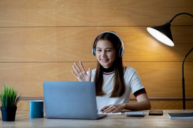 İnternette çalışmak için dizüstü bilgisayar kullanan güzel bir Asyalı kadın, çevrimiçi çalışıyor. Sınıfta bir salgını önlemek için COVID-19 salgını nedeniyle çevrimiçi öğrenme kavramı.