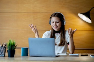 İnternette çalışmak için dizüstü bilgisayar kullanan güzel bir Asyalı kadın, çevrimiçi çalışıyor. Sınıfta bir salgını önlemek için COVID-19 salgını nedeniyle çevrimiçi öğrenme kavramı.
