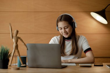 İnternette çalışmak için dizüstü bilgisayar kullanan güzel bir Asyalı kadın, çevrimiçi çalışıyor. Sınıfta bir salgını önlemek için COVID-19 salgını nedeniyle çevrimiçi öğrenme kavramı.