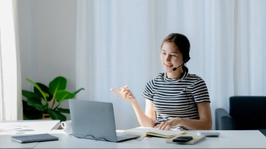 Sınıfta öğretmen ve arkadaşa iş sunan güzel Asyalı kadın, İnternet 'te okuyor. Sınıfta bir salgını önlemek için COVID-19 salgını nedeniyle çevrimiçi öğrenme kavramı.