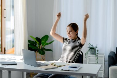 Asyalı bir kadın sınav sonuçlarını inceledikten sonra mutlu görünür, o bir üniversite öğrencisidir, COVID-19 salgını nedeniyle internette öğrenim kavramı sınıfta bir salgını önlemek içindir..