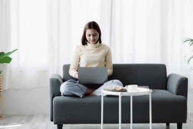 Kadın evdeki oturma odasındaki kanepede dizüstü bilgisayarda oynuyor, yoğun bir günün ardından hafta sonları dinleniyor, film izleyerek ve tabletinde müzik dinleyerek rahatlıyor. Tatil kavramı.