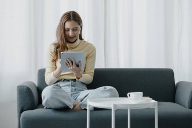 Bir kadın evdeki oturma odasındaki kanepede bir tablet çalar, yorucu bir iş gününden sonra hafta sonları dinlenir, film izleyerek ve tabletinde müzik dinleyerek dinlenir. Tatil kavramı.