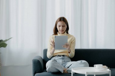 Bir kadın evdeki oturma odasındaki kanepede bir tablet çalar, yorucu bir iş gününden sonra hafta sonları dinlenir, film izleyerek ve tabletinde müzik dinleyerek dinlenir. Tatil kavramı.