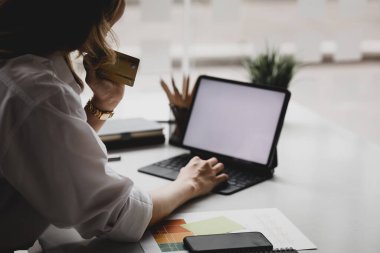 Kredi kartı tutan güzel bir kadın, internet üzerinden mal ve hizmetleri ödemek için kredi kartı kullanıyor, online alışveriş için kredi kartı kullanma kavramı, internet sitesinden mal ve hizmet sipariş etme kavramı.