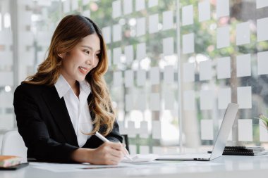 Bir iş kadını şirketin mali belgelerini kontrol ediyor ve bir mesajlaşma programı aracılığıyla finans müdürüyle konuşmak için dizüstü bilgisayar kullanıyor. Şirket mali yönetimi kavramı.