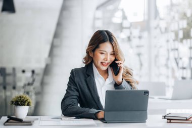 Asian woman talking on the phone, she is a salesperson in a startup company, she is calling customers to sell products and promotions. Concept of selling products through telephone channels.