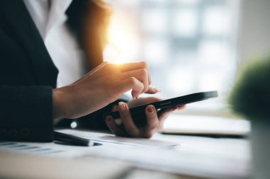 Cep telefonundan mali bilgilere bakan genç bir iş kadını, şirketin mali belgelerini kontrol ediyor, yeni kurulan bir şirketin kadın yöneticisidir. Mali yönetim kavramı.