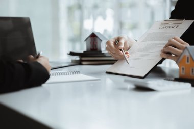 The salesperson and the customer are discussing the details together, the salesperson introduces the house details and the housing information before agreeing to sign the sale. house sale idea.
