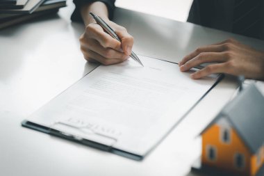 Real estate salespeople are reviewing the real estate sales contract documents before the customer agrees to sign the contract to buy the housing in the project. Real estate trading concept.