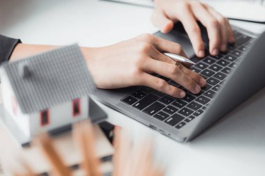 Klavyeye yakın çekim el yazması, satış elemanı müşteriye işlem detaylarını açıklamak ve banka kredisine yardım etmek için sözleşmeyi hazırlıyor. Gayrimenkul ticareti