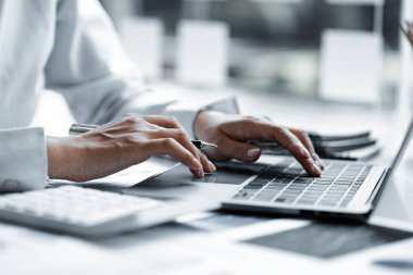 A business women working in a private room, He is typing on a laptop keyboard, He uses a messenger to chat with a partner. Concept of using technology in communication.