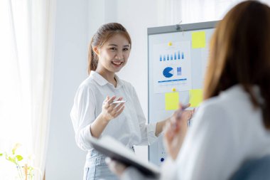 Atmosphere in the office of a startup company, two female employees are discussing, brainstorming ideas to work on summaries and marketing plans to increase sales and prepare reports to managers.