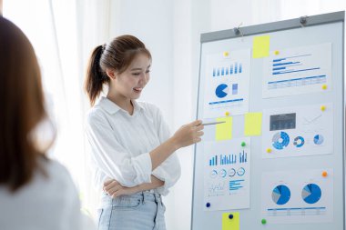 Atmosphere in the office of a startup company, two female employees are discussing, brainstorming ideas to work on summaries and marketing plans to increase sales and prepare reports to managers.