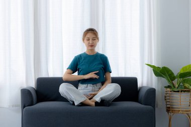 Kanepede oturan kadın yoga pozları veriyor. O, tatilde oturma odasındaki kanepede dinleniyor. Yoga pozları verip yorucu bir iş gününden sonra rahatlıyor. Sıkı çalışmaya ara verme fikri..