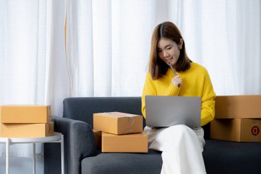 Owner of the online store on the website is preparing the parcels to send to the customers according to the orders from the web page, she is checking the information and preparing to deliver the goods