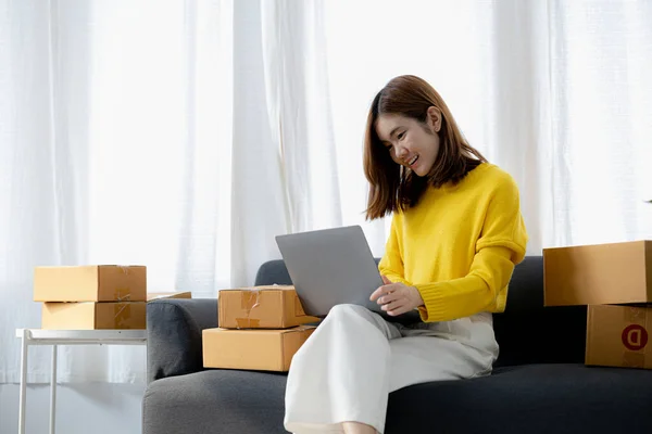 Owner of the online store on the website is preparing the parcels to send to the customers according to the orders from the web page, she is checking the information and preparing to deliver the goods