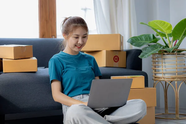 The owner of the online store on the website is preparing the parcels to send to the customers according to the orders from the web page, she is checking the information and preparing to deliver the goods.