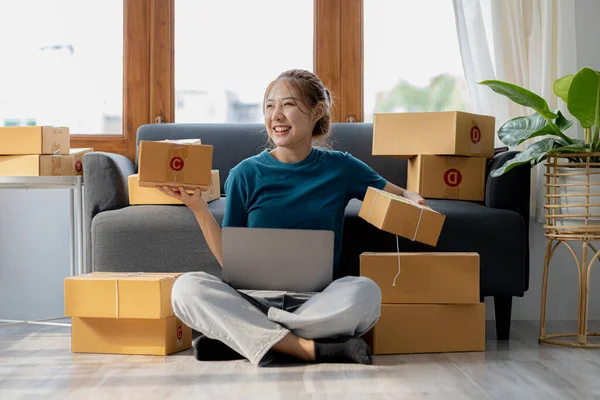 Owner of the online store on the website is preparing the parcels to send to the customers according to the orders from the web page, she is checking the information and preparing to deliver the goods