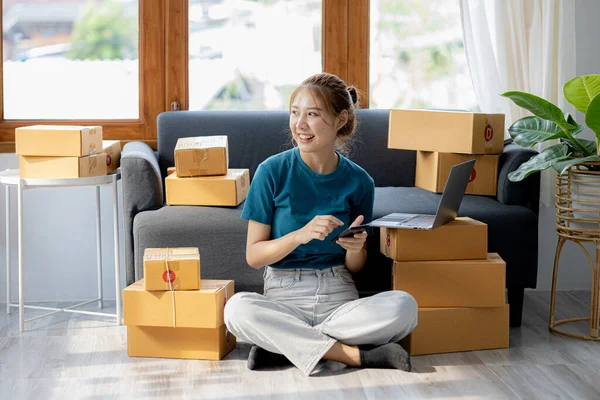 Owner of the online store on the website is preparing the parcels to send to the customers according to the orders from the web page, she is checking the information and preparing to deliver the goods