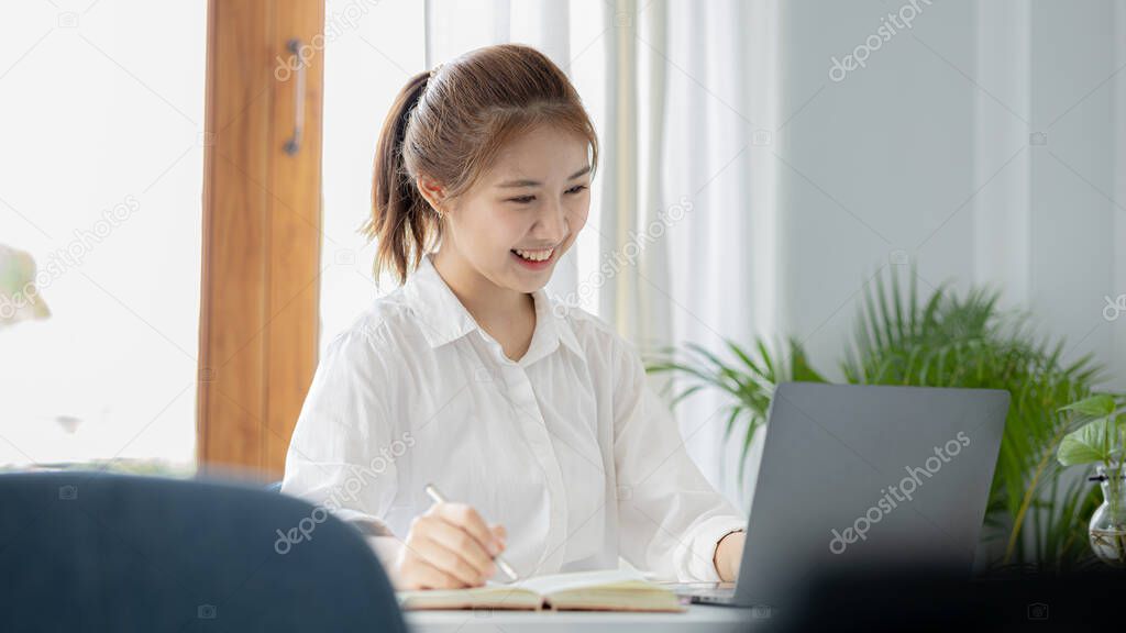 A beautiful Asian businesswoman sitting in her private office, she is checking company financial documents, she is a female executive of a startup company. Concept of financial management.