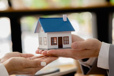 Real estate agents are carrying a housing model of the project to be forwarded to customers as home delivery. Real estate trading ideas and bank loans for buying and selling houses and land.