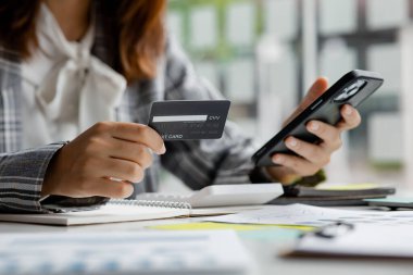 Beautiful woman holding a credit card, she uses a credit card to pay for goods and services online, the concept of using a credit card for online shopping, ordering goods and services on the website.