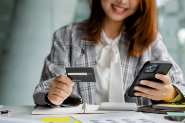 Beautiful woman holding a credit card, she uses a credit card to pay for goods and services online, the concept of using a credit card for online shopping, ordering goods and services on the website.