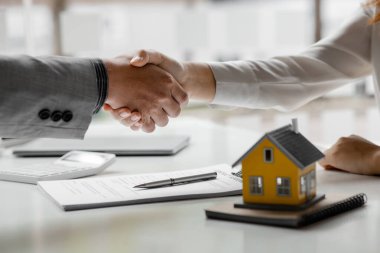 Konut kredisinin satış temsilcisi ve müşteri sözleşmeyi başarıyla imzaladıktan sonra el sıkışıyor. Konut ve gayrimenkul satma kavramı.