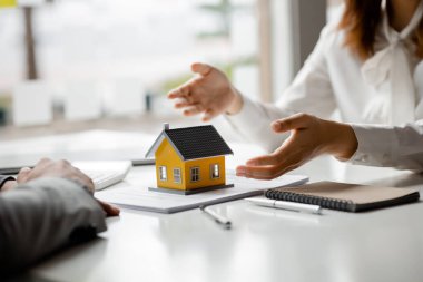 Real estate agents explain models of housing estates in projects to elaborate to clients, explaining and presenting information about homes and purchasing loans. Real estate trading concept.