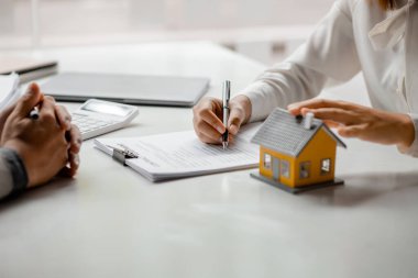 Bir kiralama şirketi çalışanı, kira sözleşmesi imzalamayı kabul eden müşterinin kira şartlarını ve koşullarını açıklayan maliyetini hesaplıyor. Ev ve gayrimenkul kiralama fikirleri.