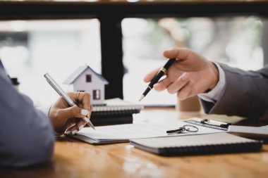 Kiralama şirketi çalışanı, müşteri kira sözleşmesini imzalamadan önce kira sözleşmesinin detaylarını ve şartlarını açıklamadan önce detayları tartışıyor. Emlak kiralama fikirleri.