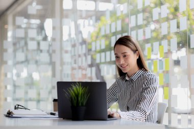 Beautiful Asian young woman looking at information on a laptop, concept image of Asian business woman working smart, modern female executive, startup business woman, business leader woman.