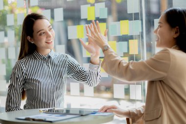 Keyif veren ve laptoplarındaki verilere bakan iki kadın, satış hedeflerini aşan ve kârlı bir büyüme sağlayan aylık satış özetine bakan iki iş kadını. Satış yönetimi kavramı