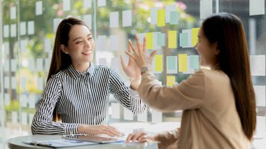 Keyif veren ve laptoplarındaki verilere bakan iki kadın, satış hedeflerini aşan ve kârlı bir büyüme sağlayan aylık satış özetine bakan iki iş kadını. Satış yönetimi kavramı